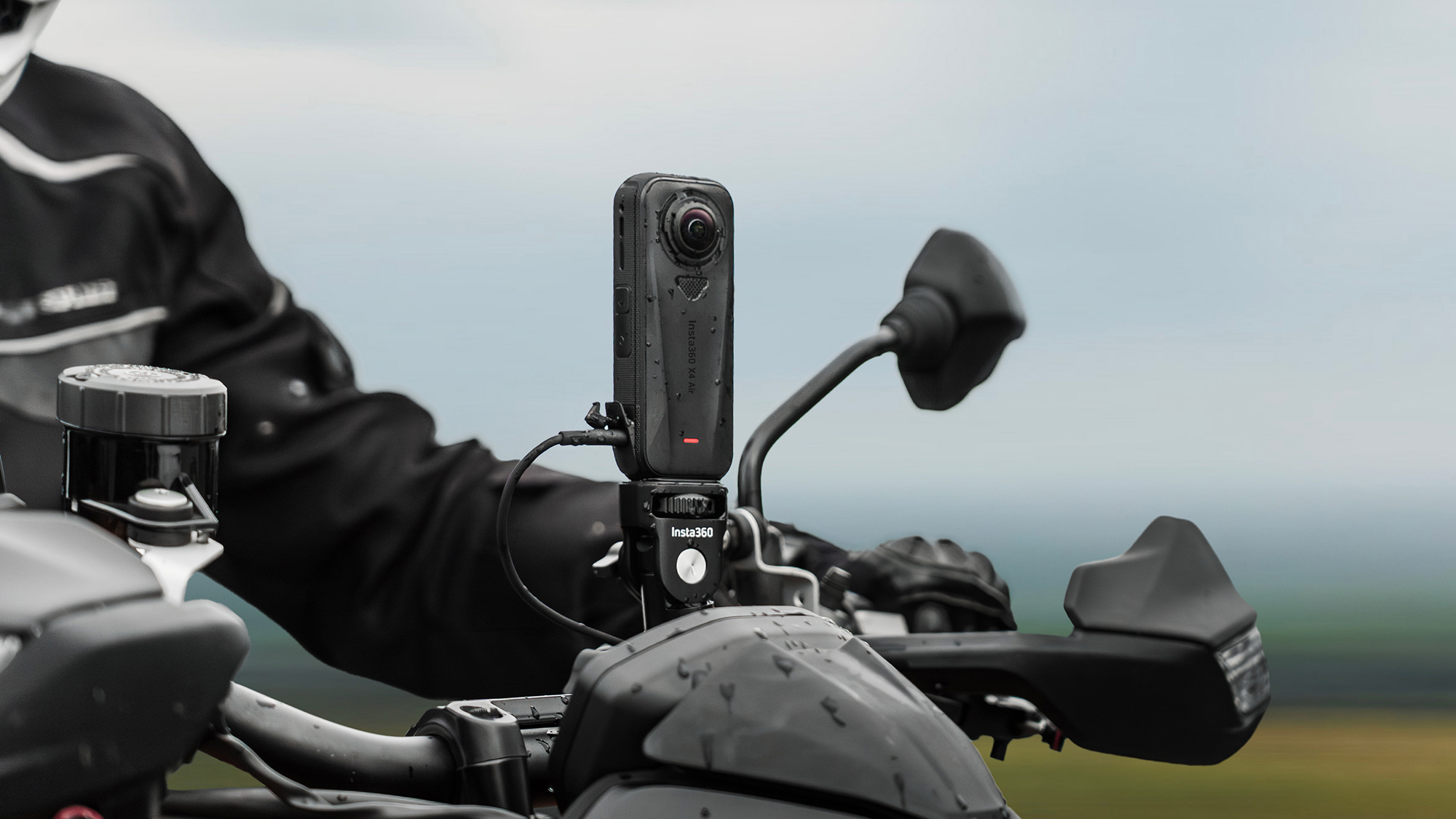 A close-up view of an Insta360 X4 Air camera securely mounted to a motorcycle handlebar.