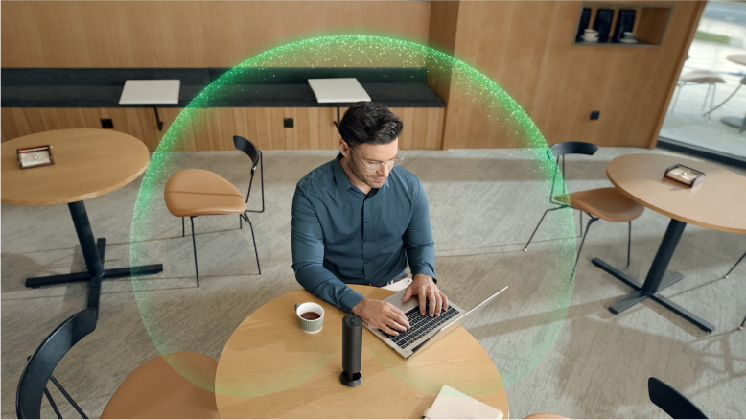 Man sat at a desk working on his laptop, using Insta360 Wave with its precise cardioid pickup pattern to hear clearly.