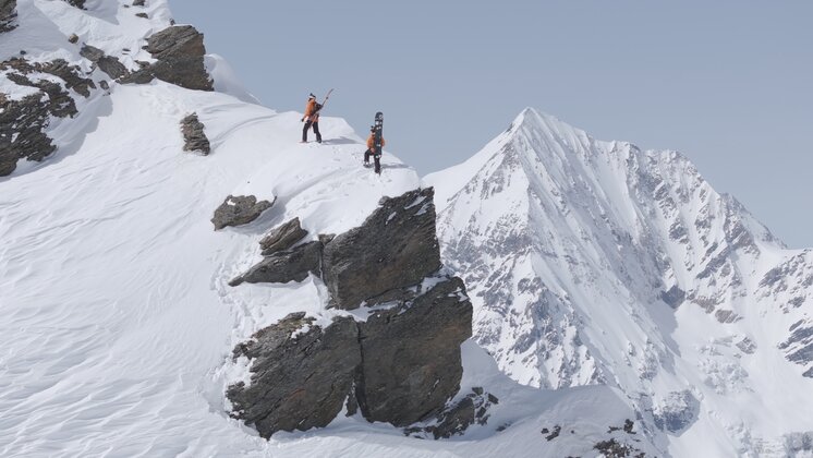 The Weger Brothers climbing a mountain with snowboards on their backs.