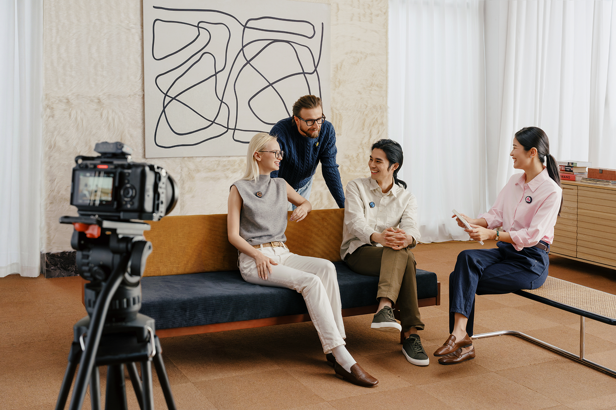 Four people conducting a casual interview on a sofa while all using Insta360 Mic Pro wireless microphones, all linked up to one camera.
