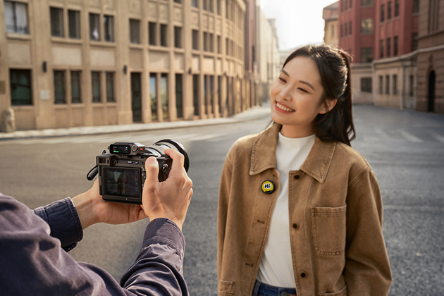 A woman is seen vlogging with a DSLR camera and Insta360 Mic Pro mounted on her jacket.