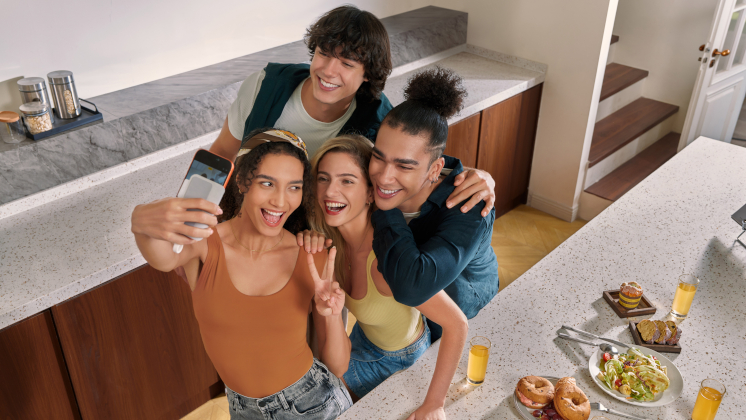 A group of friends taking a selfie on their mobile phone's main rear camera by using Insta360 Snap Selfie Screen, allowing them to take a higher-quality 0.5× selfie.