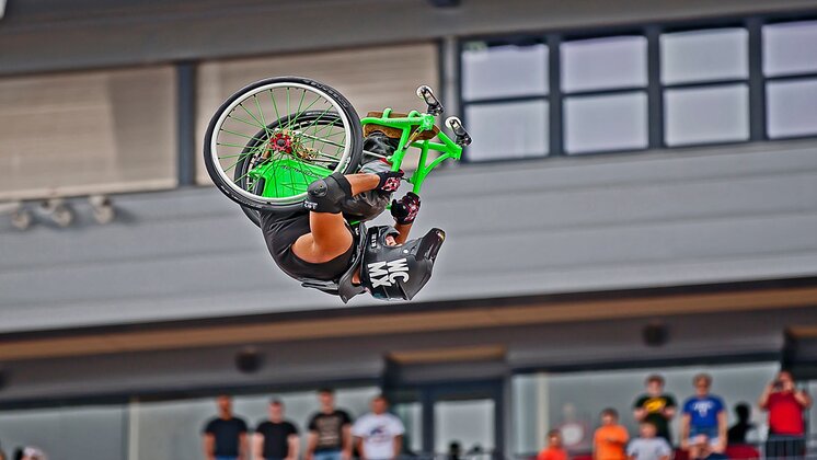 Aaron “Wheelz” Fotheringham, the inventor of wheelchair motocross, performing a backflip on his signature green wheelchair.