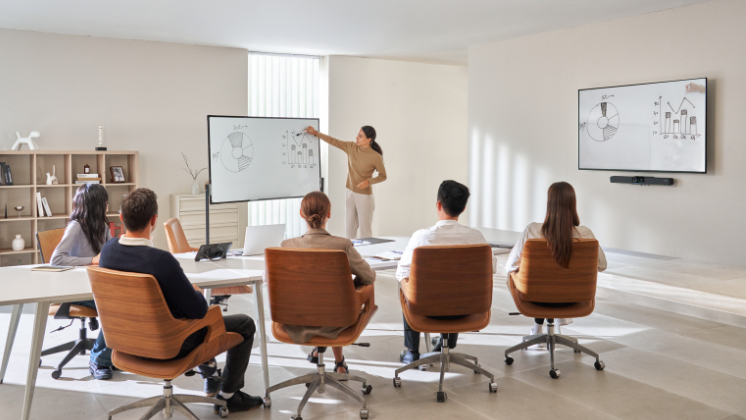 Modern SMB workspace showing a presenter leading a meeting with Insta360 Connect video bar enhancing audio and video for hybrid teams.