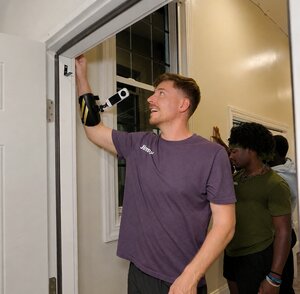 MrBeast touching a white door frame inside of a house for his latest challenge. An Insta360 camera is strapped to his wrist.